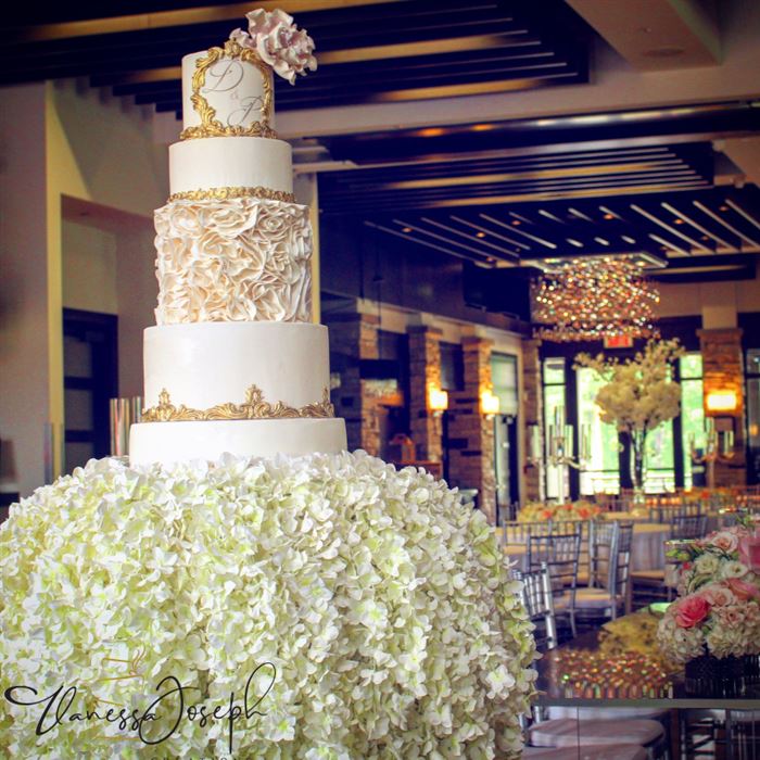 gâteau de mariage royal blanc et or sur une cascade de fleurs