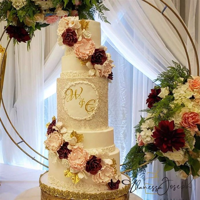 White wedding cake with pink, burgundy and gold flowers