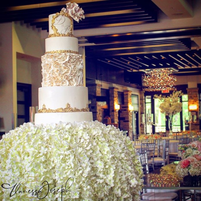 Royal white and gold wedding cake on a cascade of flowers