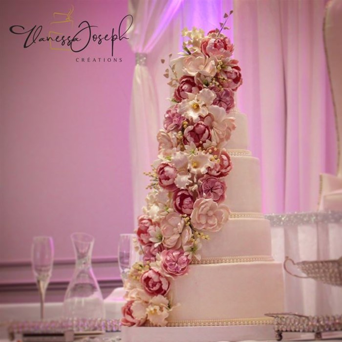 White wedding cake with cascades of fuchsia pink, pale pink and white flowers