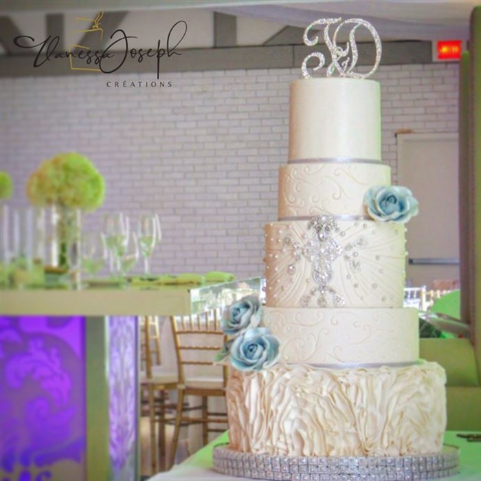 white wedding cake with blue flowers and silver jewelry