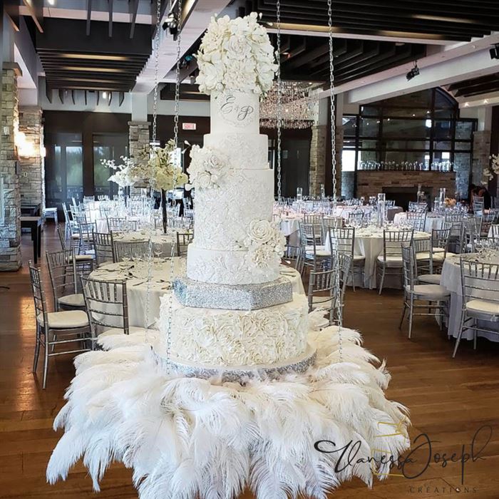 gâteau de mariage blanc et argent suspendu sur plumes blanches