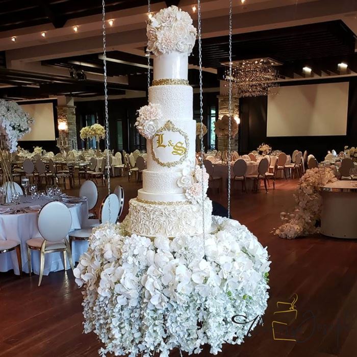 gâteau de mariage blanc et or suspendu sur fleurs
