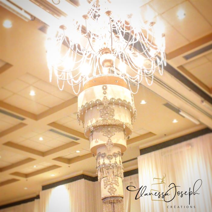 gâteau de mariage royal blanc et or renversé suspendu au plafond avec chandelier
