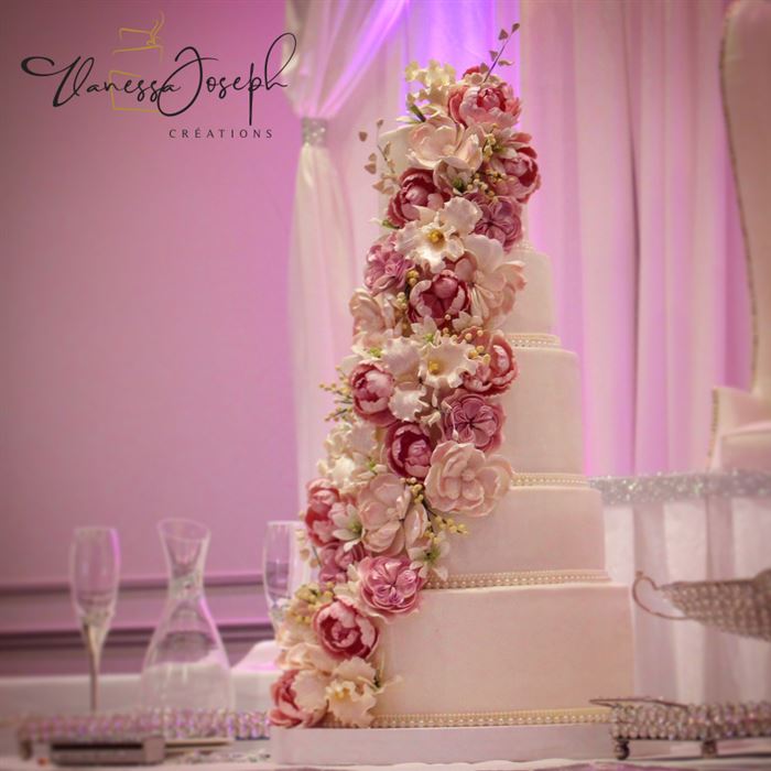 gâteau de mariage blanc avec cascades de fleurs rose fuchsia, roses pâles et blanches 