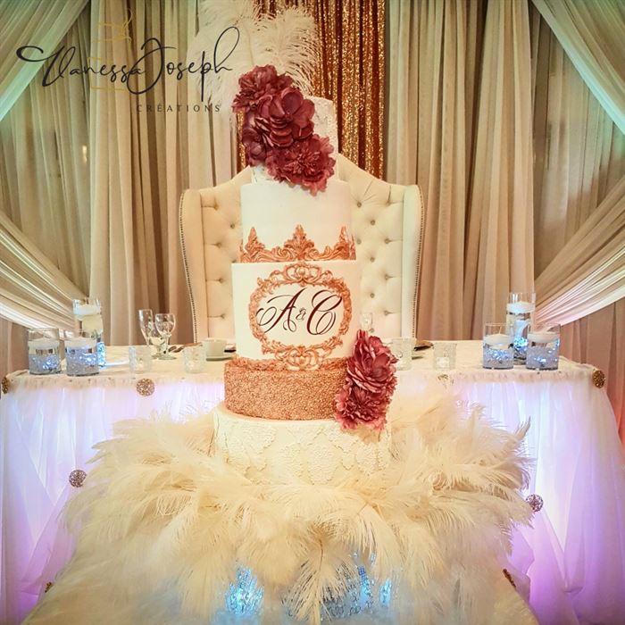 gâteau de mariage blanc, or rose avec fleurs roses, sur plateau de plumes blanches
