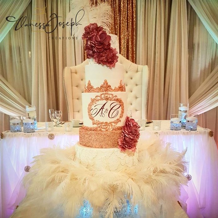 white and rose gold wedding cake with pink flowers on white feathers